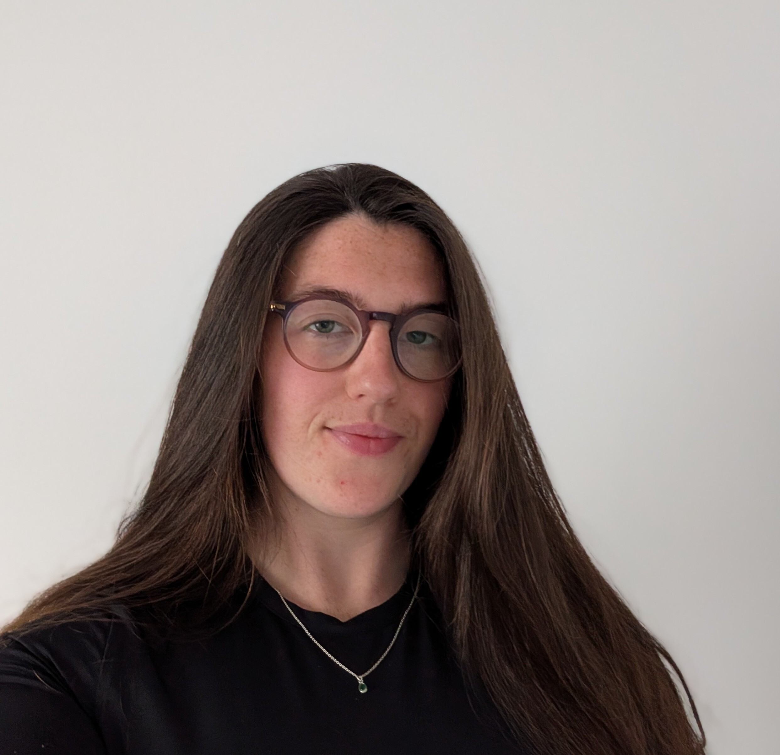 A photo of Niamh with long dark hair and glasses looking straight into the camera with a slight smile
