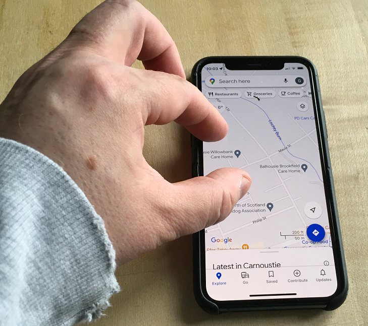 A person using pinch-to-zoom to zoom into/out of a map within the Google Maps app on iOS