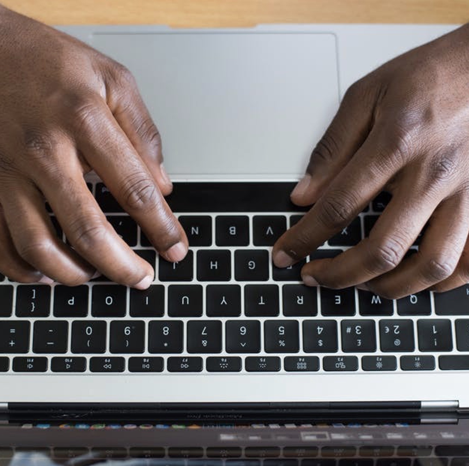 A person's hands typing on a MacBook Pro keyboard